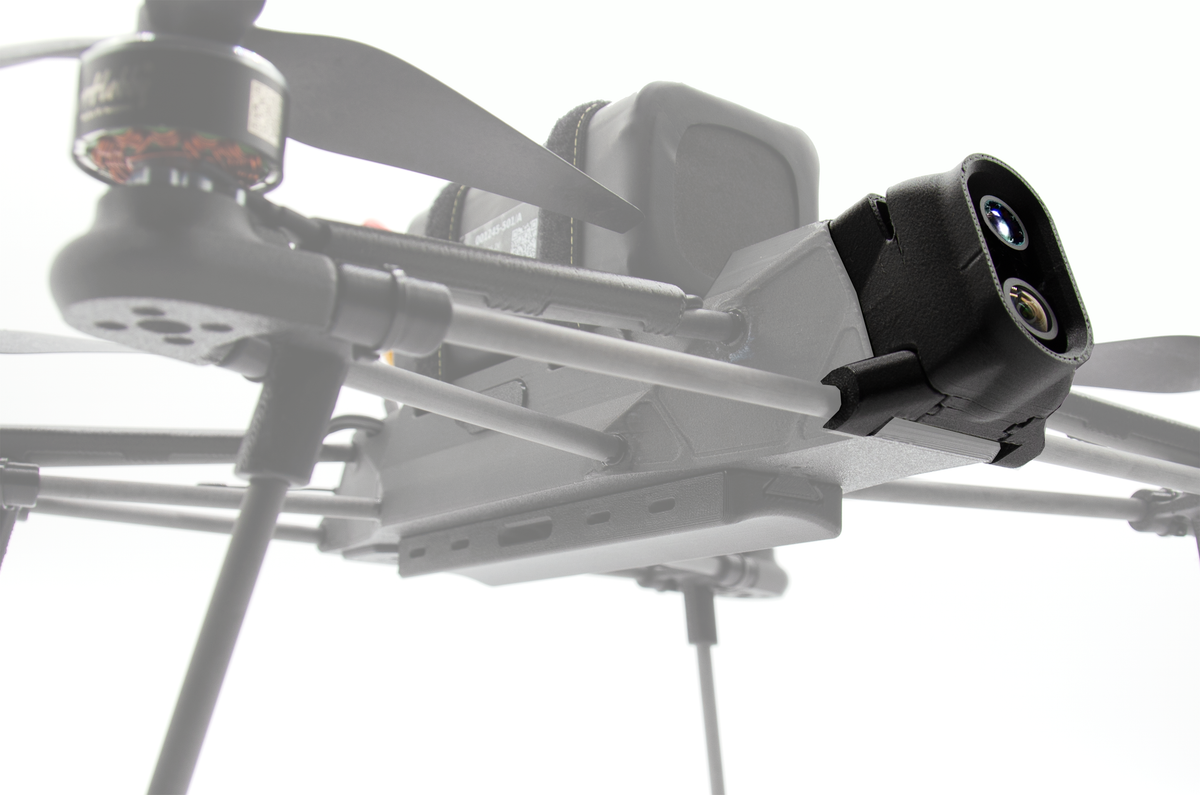 A close-up of a gray quadcopter drone with a black camera mount attached to the side, photographed against a bright white background.