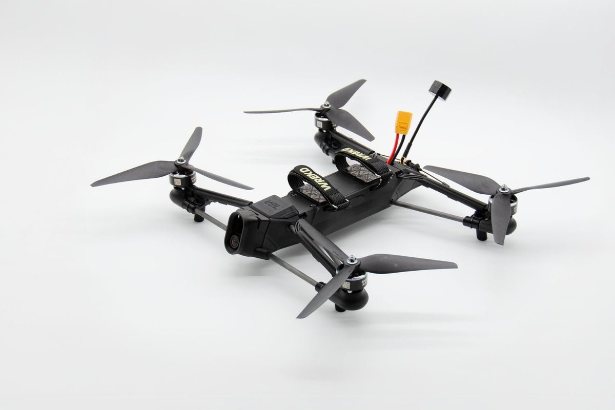A black quadcopter drone with four gray propellers, a mounted camera, and a yellow connector on a clean white background.