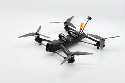 A black quadcopter drone with four gray propellers, a mounted camera, and a yellow connector on a clean white background.