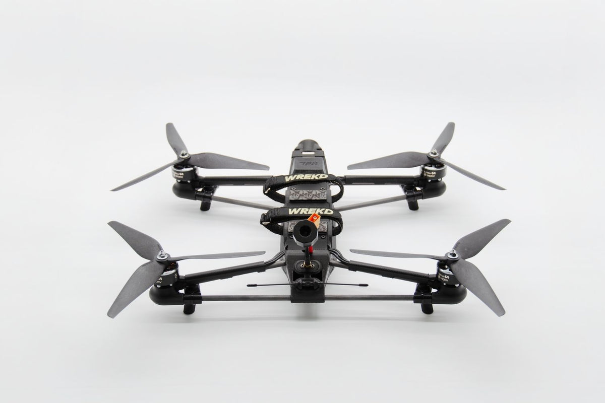 A black quadcopter drone with four gray propellers, featuring a camera lens on the front and visible 'WREKD' branding, photographed from a top-down angle on a white background.