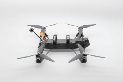 A black quadcopter drone with four gray propellers, shown from a top-down perspective on a clean white studio background.