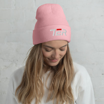 Woman wearing a pink beanie with 'TER' embroidery against a light gray background