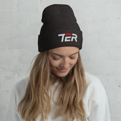 Woman wearing a black beanie with 'TER' logo against a light gray background