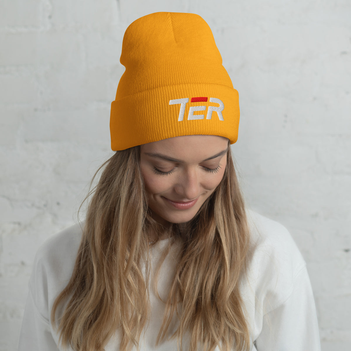 Person wearing a yellow beanie with 'TER' text against a light gray background
