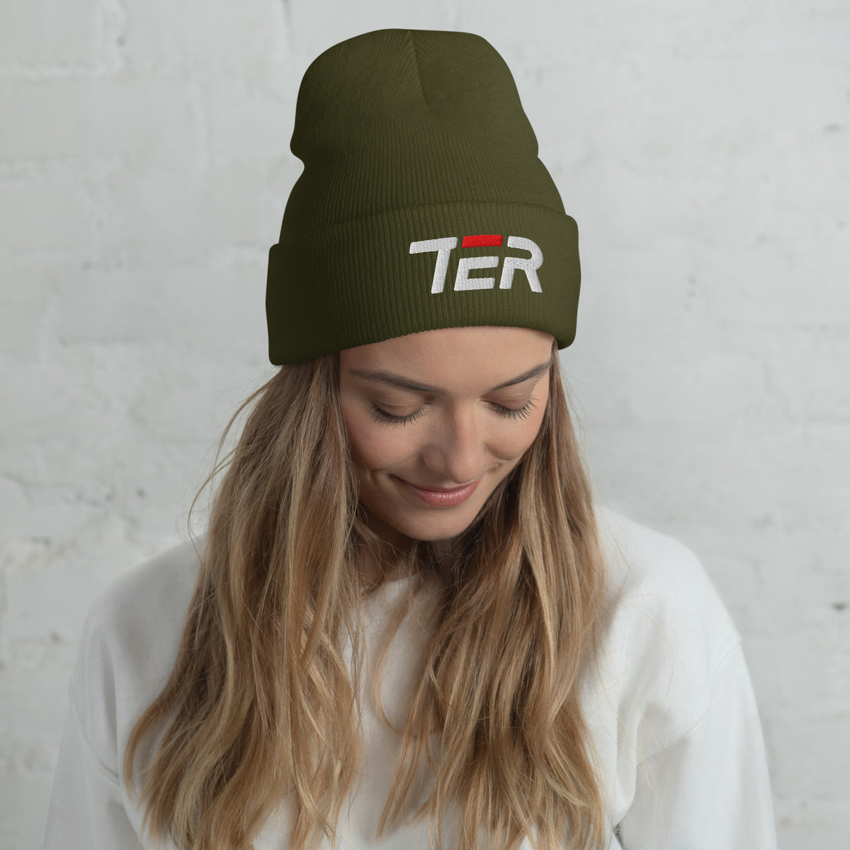 Woman wearing a green beanie with 'TER' text against a light gray background